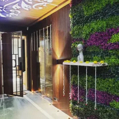 We designed this elegant entryway to welcome residents home with a touch of nature. The combination of a lush vertical garden with purple accents, warm wood louvers, and soft up-lighting creates a sophisticated and serene first impression.