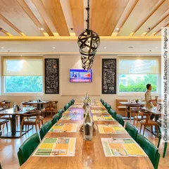 The long community table at Citrus Cafe, Bengaluru, is perfect for large groups or co-working. The design is anchored by striking pendant lights and a slatted wood ceiling detail.