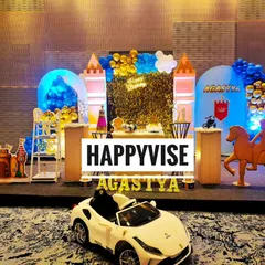 A royal prince theme for Agastya's first birthday. The setup features a castle backdrop, a golden shimmer wall, and even a miniature luxury car for the little prince to make a grand entrance.