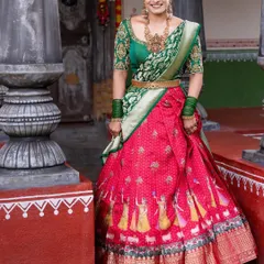 A full-length view of a client wearing a traditional red and green half saree. The skirt features unique motifs, adding a special touch to this classic ensemble.