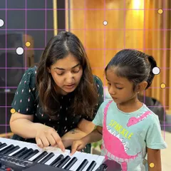 It's never too early to start! A mentor patiently teaches one of our youngest students the basics of the piano, making learning fun and accessible for the 4 to 11 age group.