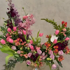 This Wabi Sabi arrangement celebrates beauty that is imperfect and incomplete. The crescent shape is formed with pink tulips, orchids, and roses, creating a sense of gentle, organic movement.