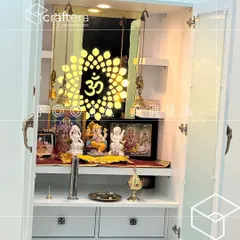 A close-up of a beautifully lit pooja area. The backlit 'Om' symbol, crafted with CNC cutting, serves as a divine centerpiece, creating a warm and spiritual focal point within the cabinet.