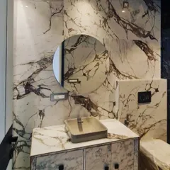 This bathroom design uses a stunning white and brown veined marble for the walls and vanity, creating a bold and creative space.