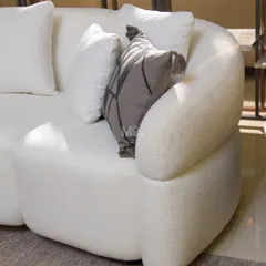A closer look at the Aether Sofa's distinctive curved arm. The high-quality bouclé fabric adds visual depth and a touch of cozy sophistication, making it a perfect piece for modern, serene interiors.