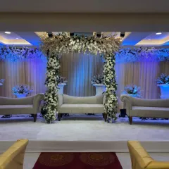 An elegant white floral stage setup at Palm Beach banquet in Vashi. The floral arch and matching sofas create a classic and timeless look for a wedding or reception.