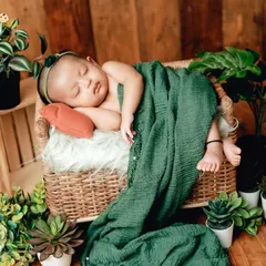 This setup uses a wicker basket and lots of greenery for a fresh, botanical feel. The soft green blanket complements the natural theme perfectly.