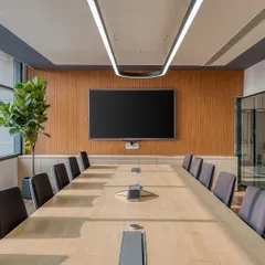 The main conference room at Laurus Labs. A wood-paneled feature wall and minimalist lighting create a professional and focused environment, with large windows providing ample natural light.