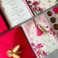 A flat-lay of our P&A engagement invitation suite. The design features a vibrant pink lotus theme with a vellum overlay, silk tassels, and a matching handmade paper envelope sealed with wax.