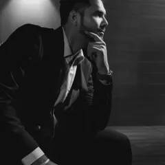 A classic, thoughtful black and white portrait of the groom in his suit, captured with dramatic lighting.