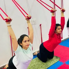 Using the wall ropes for support in a kneeling backbend helps to build upper body strength and open the shoulders, preparing the body for deeper postures.