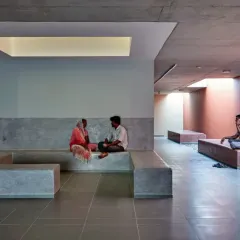In this institutional waiting area, skylights are integrated with built-in concrete seating. The light defines distinct zones, creating more intimate spaces for conversation within a larger, open hall.