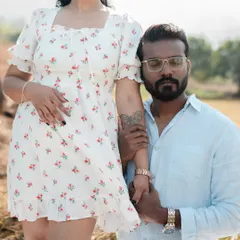 A stylish and intimate pose where a man kneels, holding his partner's arm as she stands beside him. This shot has a gentle, romantic feel, set against a beautiful natural landscape.