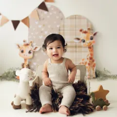 A happy sitter session with a giraffe theme. This little one is all smiles, sitting up in a miniature cart, showing off his big-boy skills.