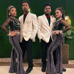 Our dance troupe ready for a show. This picture showcases one of our coordinated costume sets, featuring black tops, sparkling pants, and white blazers for the men.