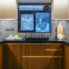 Warm wood cabinets and a dark countertop give this kitchen a cozy, rustic feel. The patterned tile floor adds a touch of vintage charm, while the large window provides ample natural light.