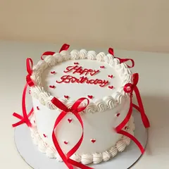 A classic white cake decorated with delicate red ribbons and tiny red hearts. This simple, coquette-style design is both timeless and romantic.