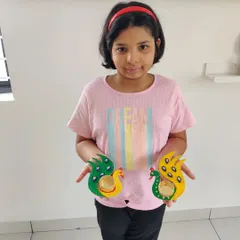 So much pride in her finished work! She made this pair of bright and colorful peacock T-light holders herself, and they are ready to light up her home for Diwali.