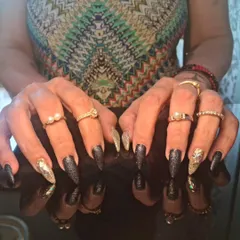 A full view of the glamorous black and holographic glitter stiletto nails.