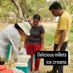 A customer trying a sample of delicious millet ice cream from a vendor's cooler.
