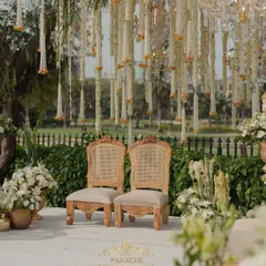 The couple's seating at the mandap, set against a backdrop of hanging floral strings and a view of the golf course. The setting is both intimate and grand.