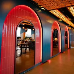 A key design feature at Bramble is this series of bold, red-tiled arches with integrated backlighting. They create a visually stunning corridor that adds depth and character to the restaurant's interior layout.
