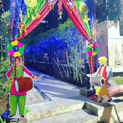 A traditional entrance gate for a Lohri or Punjabi-themed party. The colorful drapes are decorated with props and cutouts of a couple playing the dhol.