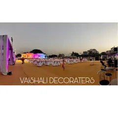 A wide, panoramic view of an outdoor evening event just as the lights come on. I arranged the entire ground with carpet, banquet seating, and a brightly lit stage to create a festive atmosphere.