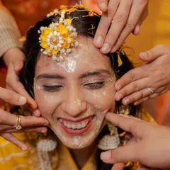 A bride's radiant smile during her Haldi ceremony. Even when covered in paste, her happiness shines through, and we make sure to capture it.