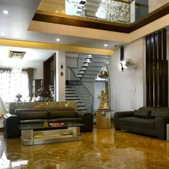 A view of a spacious, double-height living room we designed, featuring marble flooring and a modern staircase. This project showcases our work on a larger, more luxurious scale.