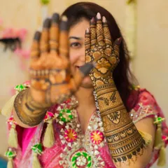 A playful pose showing off the beautiful back-of-hand mehendi. The design is rich with detail, featuring floral patterns and a personalized initial.
