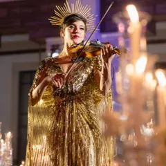 A violinist in a stunning golden gown serenades guests, adding a touch of live, ethereal music to the elegant dinner.