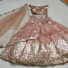 A flat-lay of the peach off-shoulder lehenga set. This view shows the coordination between the blouse, skirt, and sheer dupatta, all featuring beautiful gold work.