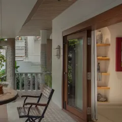 Wood-framed glass doors roll open to connect the interior to this lush green patio. The space is decorated with simple furniture and curated knick-knacks, blurring the line between indoors and out.