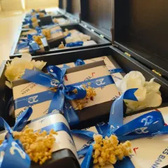 A look inside the milestone hampers, showing individually wrapped gifts with custom-branded ribbons for the "20 Years of Partnership" celebration. Every detail is carefully managed to reflect the corporate identity.