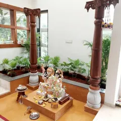 A front view of the indoor pooja garden, showing how the plants create a natural, calming backdrop for the deity. The built-in planters are filled with easy-to-maintain indoor palms.