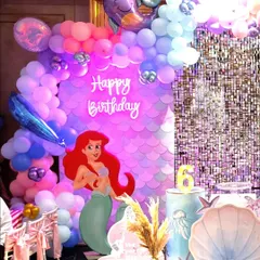 The main photo backdrop featuring a large Ariel cutout, a neon "Happy Birthday" sign, and a beautiful balloon arch with foil sea creature balloons.
