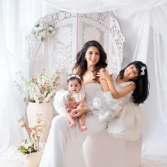 A mother's love captured in an all-white, angelic setting. This portrait with mom and her two daughters showcases the tender and playful connection they share.
