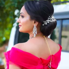 A close-up of a chic and modern bridal updo. This elegant bun is decorated with a sparkling crystal hairpiece, making it a perfect choice for a reception or cocktail event.
