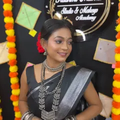A beautiful Makar Sankranti look, featuring a black saree with silver accents, paired with oxidized silver jewelry and a pop of color in the hair.