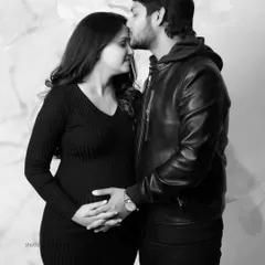 A classic black and white couple's portrait filled with tenderness. The father-to-be kisses his partner's forehead as they both hold her belly, creating a timeless and emotional image.
