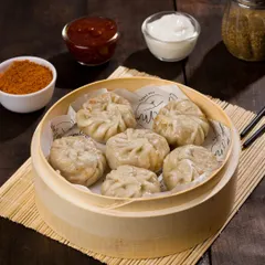 Steamed momos presented in a traditional bamboo basket, ready for a menu shoot. We style savory items with appropriate dips and garnishes to create a complete and appealing dish.