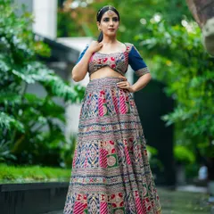 A confident, full-body pose against a green, natural background. The contrast makes the colors of the ethnic lehenga pop, perfect for a designer catalogue.