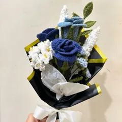 A bold and beautiful custom bouquet featuring deep blue crochet roses paired with delicate white filler flowers. The contrast with the black and gold wrapping paper creates a dramatic and sophisticated look.
