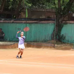 A female player mid-swing, hitting a high ball with precision during her semi-final match. Every point is a battle in our tournaments.