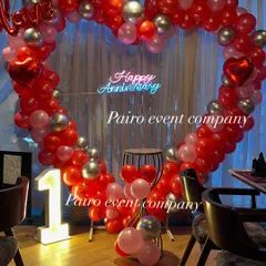 A classic first-anniversary decoration in a restaurant. This setup includes a large heart-shaped balloon arch in red and silver, a custom "Happy Anniversary" neon sign, and a light-up marquee number "1".