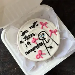 Marking the big 2-0 with humor! This cute bento cake features a crying stick figure and the text "I'm not a teen anymore," surrounded by pretty pink bows.