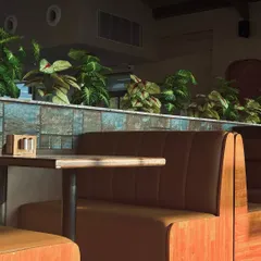 We designed these comfortable booth seating areas to offer a sense of privacy while maintaining the open feel of the restaurant. The warm tan leather upholstery is complemented by a divider wall with blue-green tiles and lush planters.