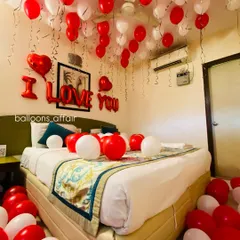 A close-up on the bed, showing the mix of red and white balloons and the clear "I LOVE YOU" banner, perfect for a romantic gesture.