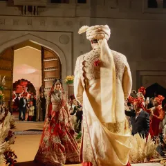 The first look. This powerful moment is framed by the aisle, lined with pampas grass and florals, leading to the grand fort-style entrance. I design the entire processional to feel like a story unfolding.